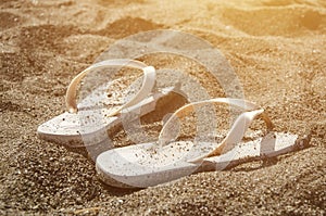 Flip flops on a black sandy beach.