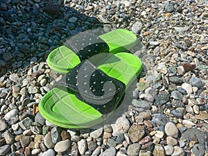 Flip-flops on the colored pebble beach. Summer and vacation concept