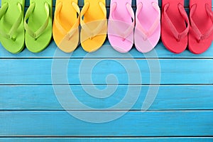 Flip flops in a row with blue beach decking, copy space