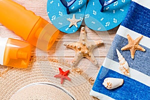 Flip flops, straw hat, starfish, sunscreen bottle, body lotion spray on wooden background top view . flat lay summer beach sea