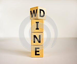 Fliped a wooden cube and changed the inscription `wine` to `dine` or vice versa. Beautiful white background, copy space