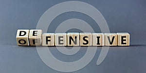 Fliped wooden cubes and changed the inscription `offensive` to `defensive` or vice versa. Beautiful grey background, copy spac