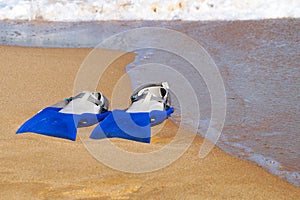 Flippers on a sandy beach near the waves, copy space