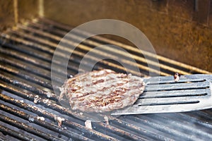 Flipping a hamburger on a hot grill