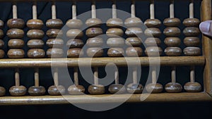 Flipping over a wooden abacus with black background. Seeds following in the same direction, together and simultaneously.