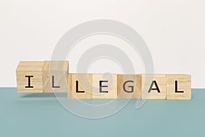Flipping two wooden cube to change the word Legal to Illegal on neutral background
