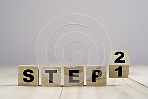 Flipping wooden cubes block for changing step 1 to step 2 on wooden table