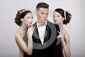 Flirtation. Handsome Man in Cuddle of Two Voluptuous Women