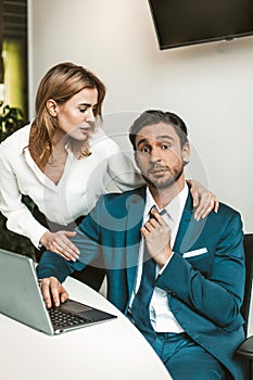 Flirtation or sexual harassment. Blonde woman seduces man working with laptop, colleagues flirt at work. Seducing a