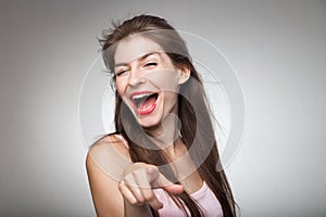 Flirtatious girl pointing on camera and winking. photo