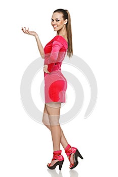 Flirtatious young woman in pink dress showing blank copy space photo
