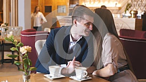 Flirting in a cafe. Beautiful loving couple sitting in a cafe enjoying in coffee and conversation