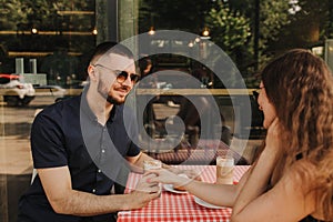 Flirting in a cafe. Beautiful loving couple sitting in a cafe enjoying in coffee and conversation. Love and romance. Blurred and