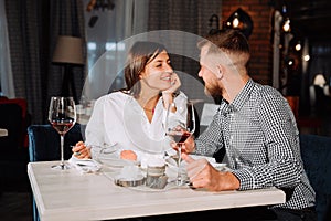 Flirting in a cafe. Beautiful loving couple sitting in a cafe enjoying in wine and conversation