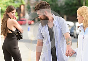 Flirting in the street. Love triangle and threesome. Man cheating his girlfriend. Bearded man looking at other girl