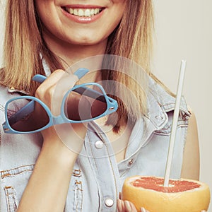 Flirty woman holding sunglasses and grapefruit