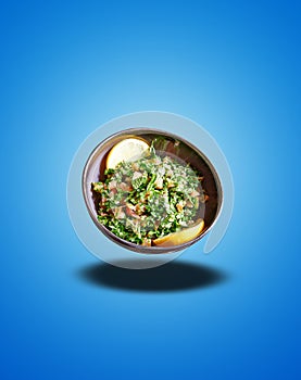 Floating Black bowl with taboule apetizer on blue gradient