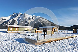 Floating Boat Dock Platform on a Frozen Snow Covered Lake with Banff Mountain Peak on Skyline