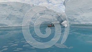 Floating boat among icebergs in ocean. Antarctica.