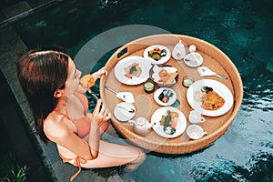 Floating breakfast in infinity pool on paradise swimming pool, morning in the tropical resort Bali, Indonesia