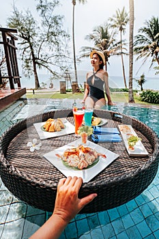 Floating breakfast in infinity pool on paradise swimming pool, morning in the tropical resort bungalow