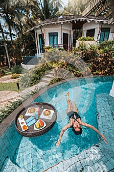 Floating breakfast in infinity pool on paradise swimming pool, morning in the tropical resort bungalow