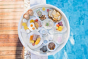 Floating breakfast set in tray with fried egg omelette sausage ham bread fruit milk juice coffee