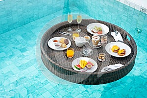 Floating Breakfast tray in swimming pool at luxury hotel or tropical resort villa, fruits; mango, watermelon dragon and passion