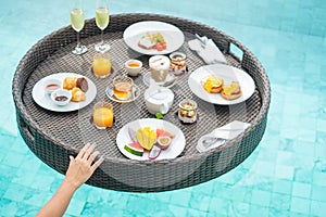 Floating Breakfast tray in swimming pool at luxury hotel or tropical resort villa, fruits; mango, watermelon dragon and passion