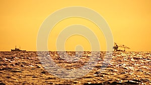 Floating Crane Vessel On Sea. Tugboat tows large crane vessel on sea horizon at sunset. Maintenance service working in