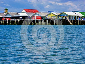 Floating fisherman village on man-made island with colorful roof and vintage houses on the blue sea with clear blue sky.