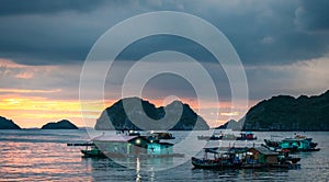 Floating Home boat in Cat Ba Island. Fisherman house boat moored in the bay in front of the city at sunset.