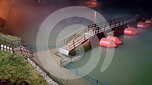 Floating pontoon bridge at foggy night and during flood