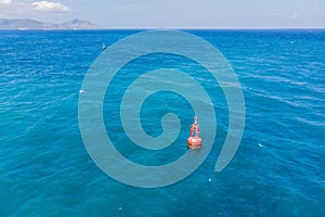 Floating red navigational buoy on blue sea, gulf. Drone