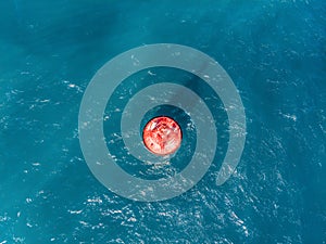Floating red navigational buoy on blue sea, gulf. Drone