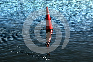 Floating red navigational buoy on blue water of Dnipro River.