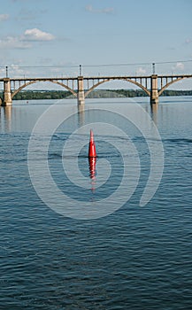 Floating red navigational buoy on blue water of Dnipro River.