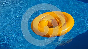 Floating ring on blue water of swimpool with waves reflecting in the summer sun