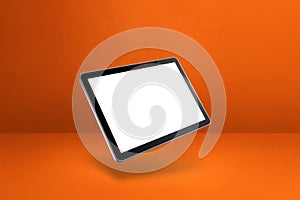Floating tablet pc computer isolated on orange. Horizontal background