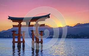 a floating tori gate in the middle of a lake at sunset