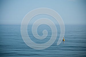 Floating yellow signal buoy on blue sea with copy space