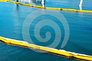 Floating yellow and white oil containment boom on calm water. Pollution concept . A containment boom is a temporary floating