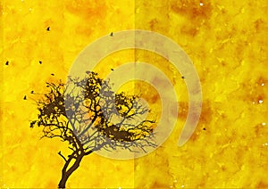 A flock of birds traveling together over a black tree on yellow orange sky background.