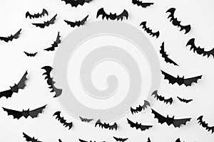 Flock of black paper bats over white background