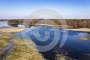 Flooded fields, meadows and forests during excessive rainfall. A river flooding fields and forests, view from a drone