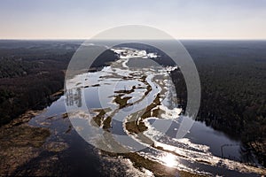 Flooded fields, meadows and forests during excessive rainfall. A river flooding fields and forests, view from a drone