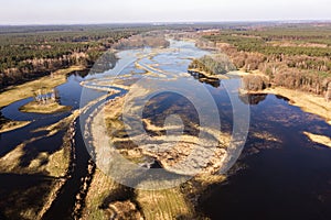 Flooded fields, meadows and forests during excessive rainfall. A river flooding fields and forests, view from a drone