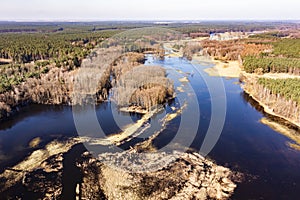 Flooded fields, meadows and forests during excessive rainfall. A river flooding fields and forests, view from a drone