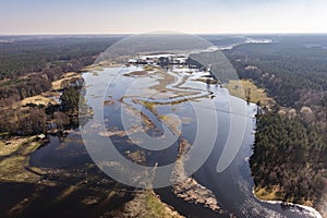 Flooded fields, meadows and forests during excessive rainfall. A river flooding fields and forests, view from a drone