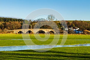 A flooded green field and the Ken Bridge at New Galloway, Scotland